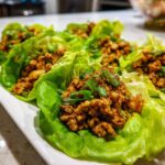 Close-up of several delicious chicken lettuce wraps filled with savory ground chicken and topped with green onions.