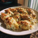 A plate of baked chicken alfredo stuffed shells covered in creamy sauce and browned, melted cheese.