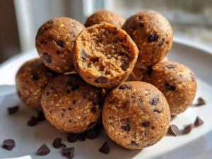 A close-up stack of homemade chocolate chip protein balls, with one cut open showing the texture inside.