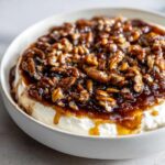 Close-up of a creamy pecan pie dip topped generously with sticky, caramelized pecans.