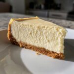 Close-up of a perfect slice of creamy No bake cheesecake showing the thick graham cracker crust.