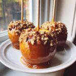Three perfect caramel apple treats coated in thick caramel and chopped nuts, resting on a white plate.