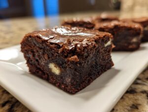 Close-up of a fudgy Oreo brownie showing a shiny top crust and white chocolate chunks inside.
