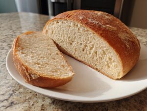 A freshly baked sourdough sandwich bread loaf, cut in half to show the soft, airy crumb texture.