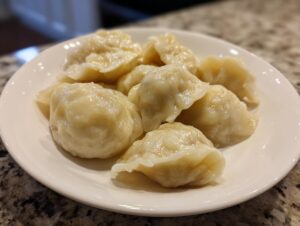 A close-up of several freshly steamed Traditional Chinese Dumplings resting on a white plate.