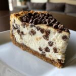 A perfect slice of chocolate chip cheesecake with a graham cracker crust and mini chocolate chips throughout and on top.