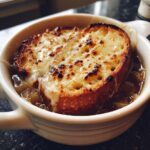 Close-up of rich french onion soup topped with a thick, cheesy, broiled crouton.