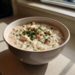 A comforting bowl of creamy chicken and rice soup, garnished with fresh parsley.