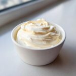 A close-up of thick, creamy fruit dip swirled beautifully in a small white bowl.