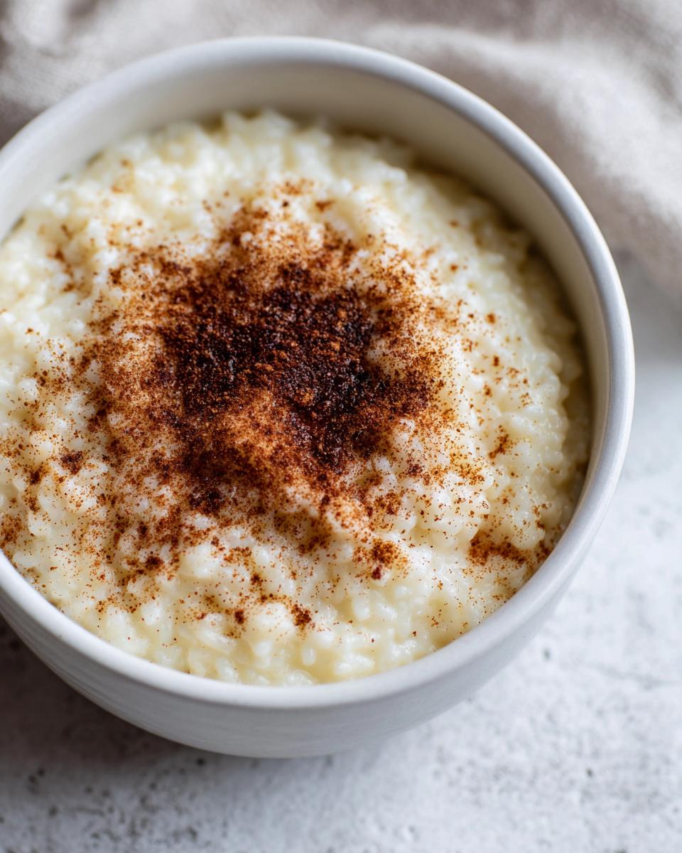 Close-up of a bowl of creamy rice pudding recipe topped generously with ground cinnamon.