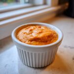 A close-up of thick, orange-hued homemade big mac sauce served in a small white fluted ramekin.