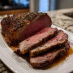 Close-up of a juicy standing rib roast, sliced to show medium-rare interior and herb crust.