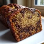 Close-up of a moist slice of chocolate chip banana bread showing rich texture and melted chocolate chunks.
