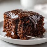 Close-up of a moist slice of chocolate pudding cake topped with rich, glossy chocolate sauce.
