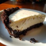 A close-up slice of no bake peanut butter pie featuring a thick, creamy filling and a dark chocolate cookie crust.