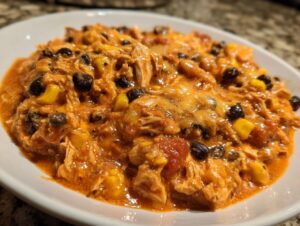 Close-up of a bowl of creamy, orange-hued slow cooker buffalo chicken chili with black beans and corn.