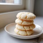 A stack of four soft, sugar-coated 3-ingredient butter cookies resting on a small, light-colored plate.