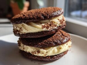 Close-up of two stacked chocolate tiramisu cookies filled with creamy mascarpone filling and dusted with cocoa powder.
