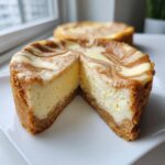 A cut mini sugar cookie cheesecake showing the thick graham cracker crust and creamy filling with a brown sugar swirl top.