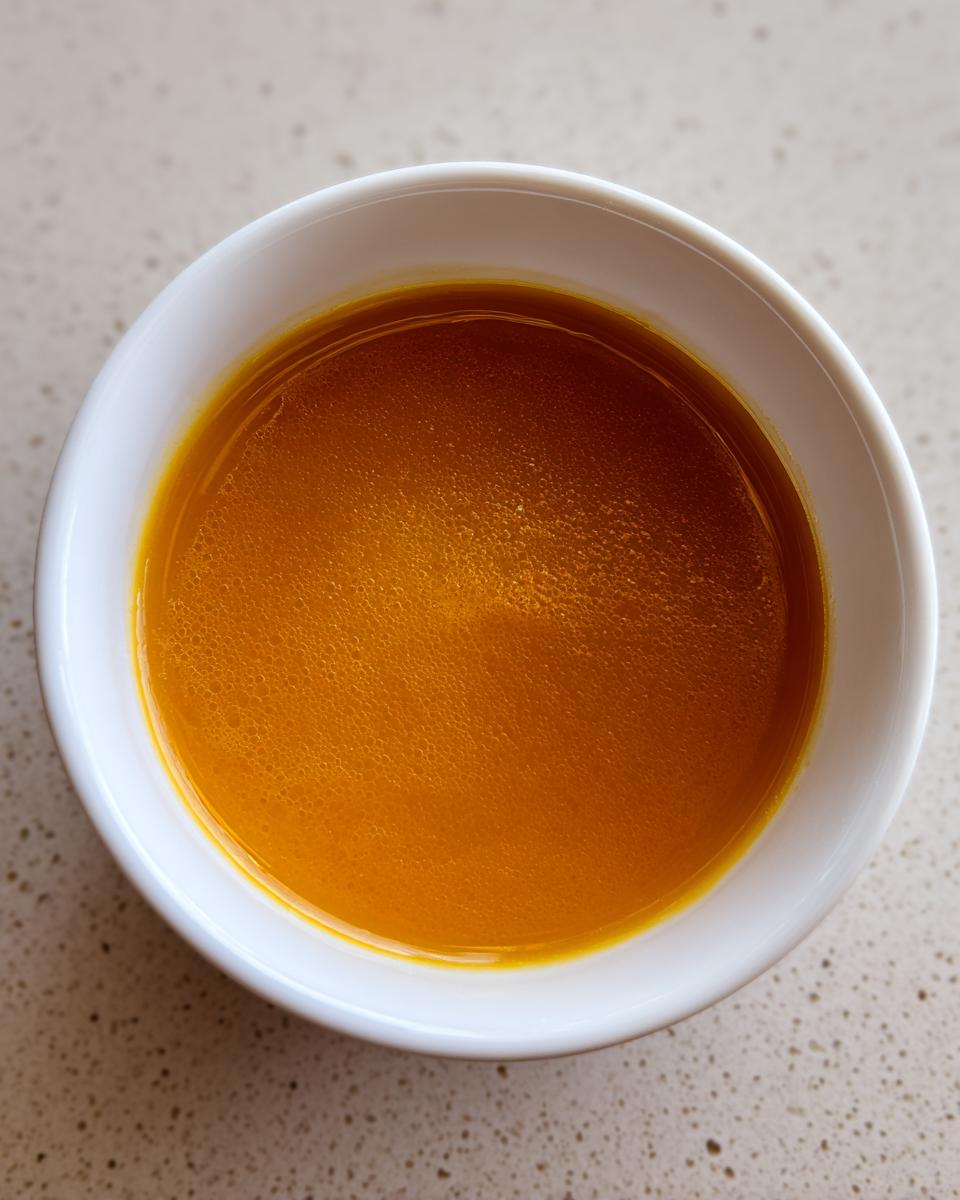 Overhead view of vibrant orange squash soup served in a small white bowl.