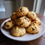 A tempting stack of golden brown cannoli cookies loaded with chocolate chips piled high on a white plate.