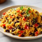 Close-up of a vibrant cilantro lime quinoa salad mixed with black beans and diced red peppers.