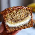 Close-up of a slice of moist cream cheese banana bread showing a thick, gooey cream cheese swirl in the center.