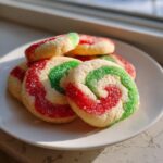 Close-up of several festive red, green, and white pinwheel cookies coated in sparkling sugar.