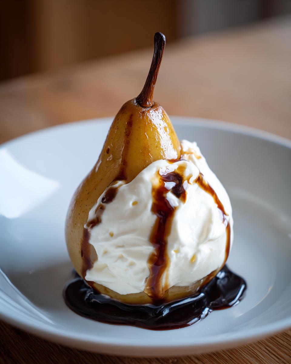 A single, beautifully caramelized poached pears topped with whipped cream and drizzled with dark syrup on a white plate.