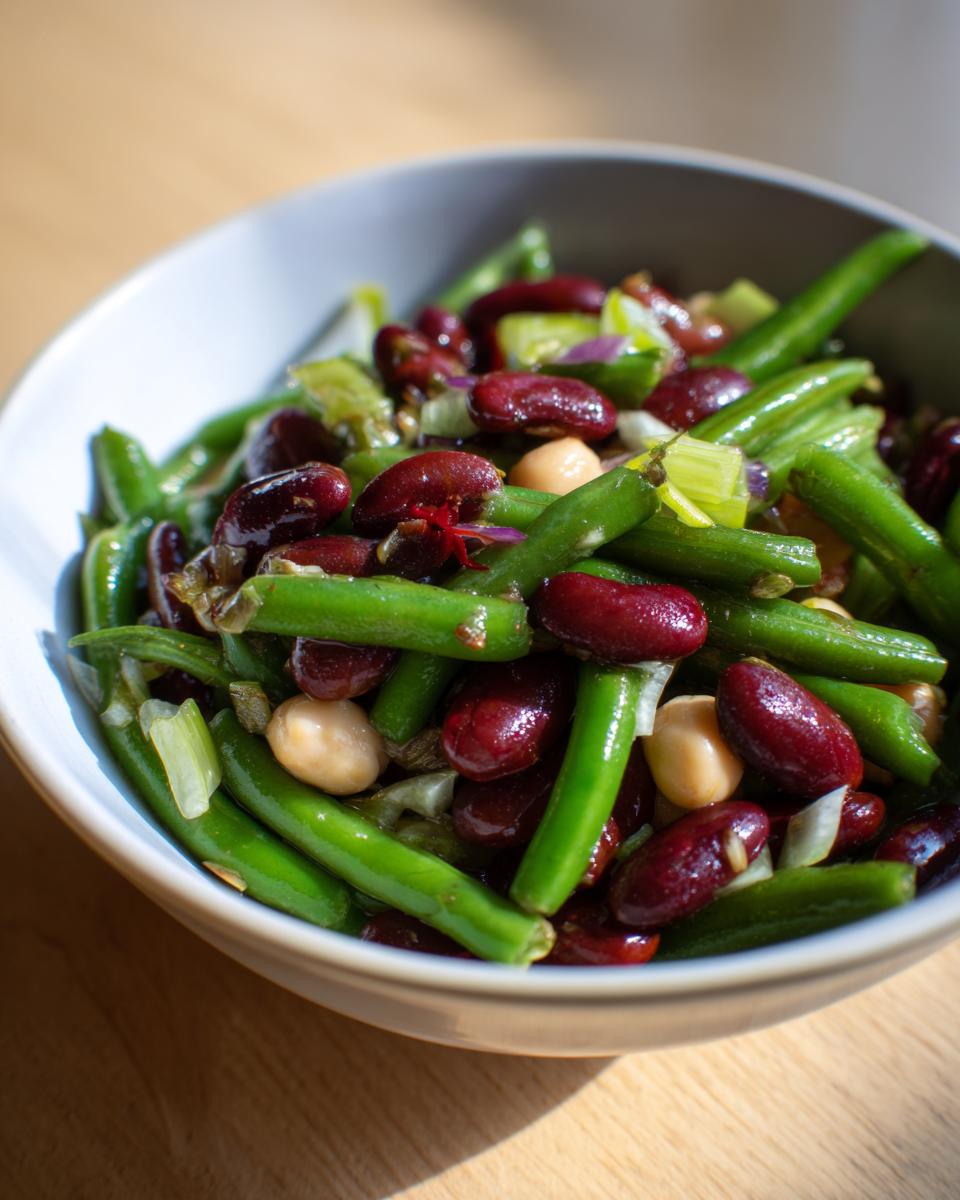 Close-up of a bowl filled with a vibrant bean salad featuring green beans, kidney beans, and chickpeas.