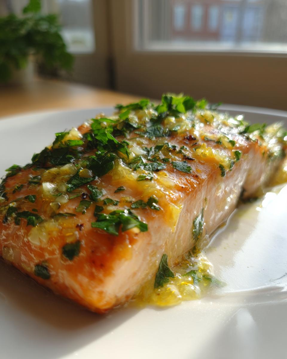 Close-up of a moist baked salmon recipe fillet topped with a bright lemon-herb glaze.