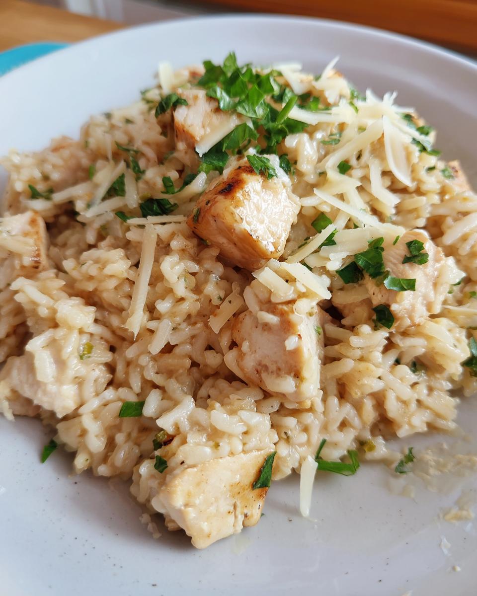 Close-up of a creamy serving of one pot chicken and rice topped with shredded cheese and fresh parsley.