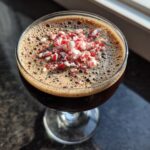 Close-up of a rich, dark peppermint espresso martini topped with a generous sprinkle of crushed red and white candy canes.