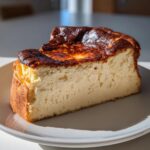 A thick slice of Basque cheesecake showing its creamy interior and deeply caramelized top.