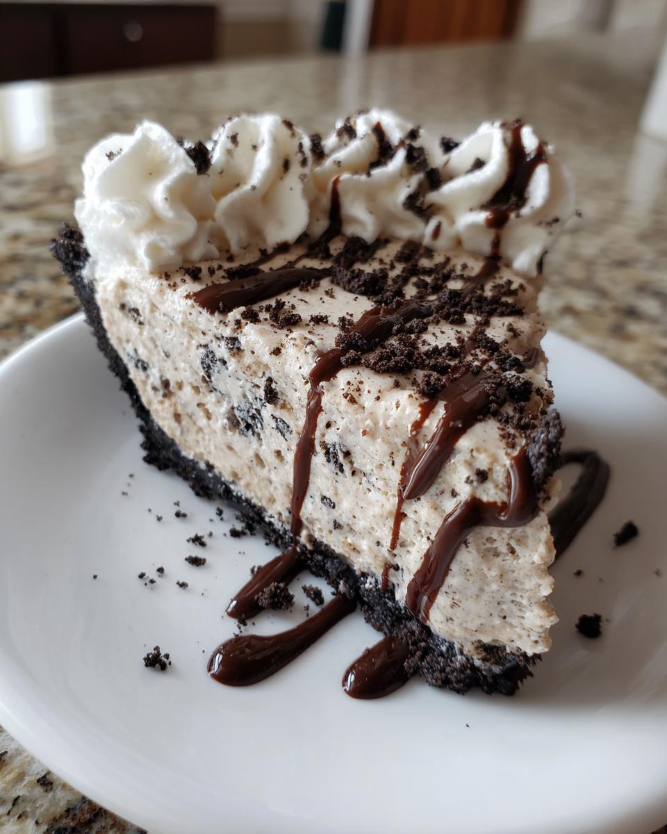 A decadent slice of cookies and cream ice cream pie with whipped cream and chocolate drizzle.