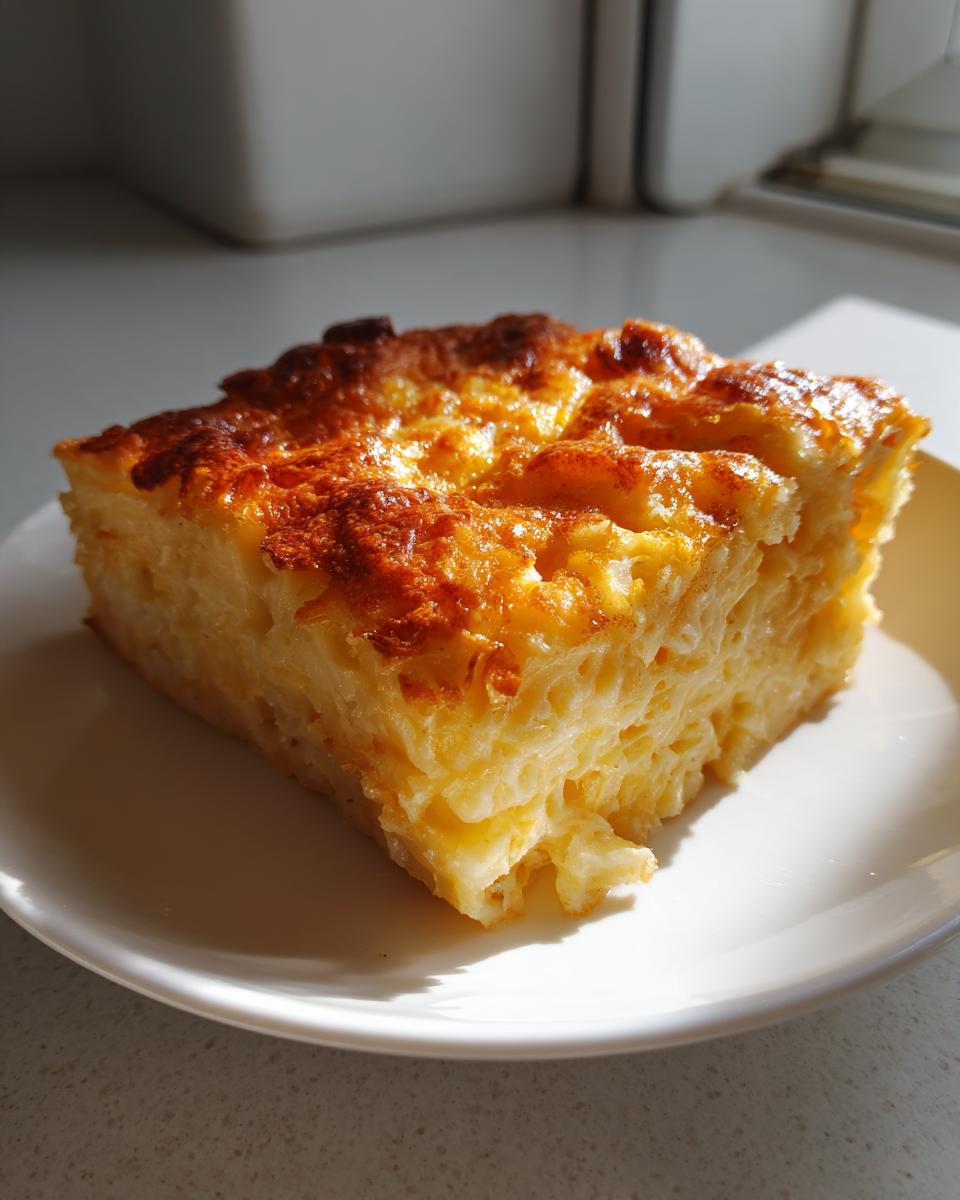 A square serving of creamy southern baked macaroni and cheese with a golden-brown, slightly crispy top, resting on a white plate.