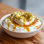 A bowl of creamy whipped ricotta dip drizzled with honey and topped with chopped pistachios.