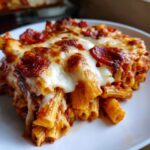 A close-up of a serving of amazing pizza pasta baked with melted mozzarella and pepperoni slices.