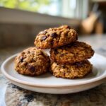 A stack of four delicious, chunky chocolate chip breakfast cookie resting on a light-colored plate.
