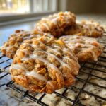 Close-up of freshly baked cinnamon toast crunch cookies drizzled with white icing, cooling on a black wire rack.