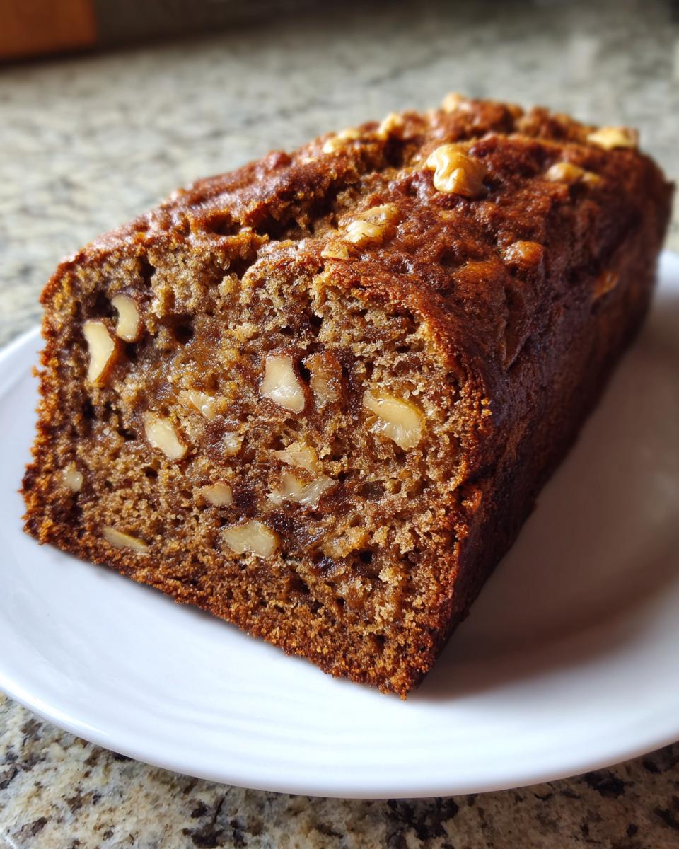 A moist loaf of cottage cheese banana bread, studded with walnuts, resting on a white plate.