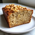 Close-up of a moist slice of cottage cheese banana bread topped with crunchy walnuts.