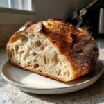Half of a freshly baked country loaf with sourdough discard showing an open, airy crumb structure.