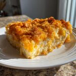 A close-up slice of creamy potato casserole topped with a golden, crunchy cornflake crust.