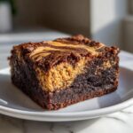A close-up of a fudgy square of peanut butter swirl brownies featuring a distinct peanut butter layer.