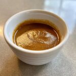 Close-up of rich, brown swedish meatball sauce in a small white bowl.