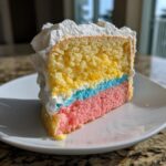Close-up of a slice of three-layer cake (yellow, blue, pink) with white frosting, perfect for a cake picnic.