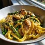 Close-up of creamy Chicken primavera featuring chicken pieces, asparagus, and peas tossed with fettuccine pasta.