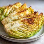 Close-up of thick wedges of fried cabbage steaks, seasoned with pepper, showing caramelized edges.