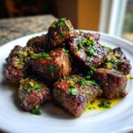 A close-up of perfectly seared Garlic Butter Steak Bites piled high and glistening with sauce and fresh parsley.
